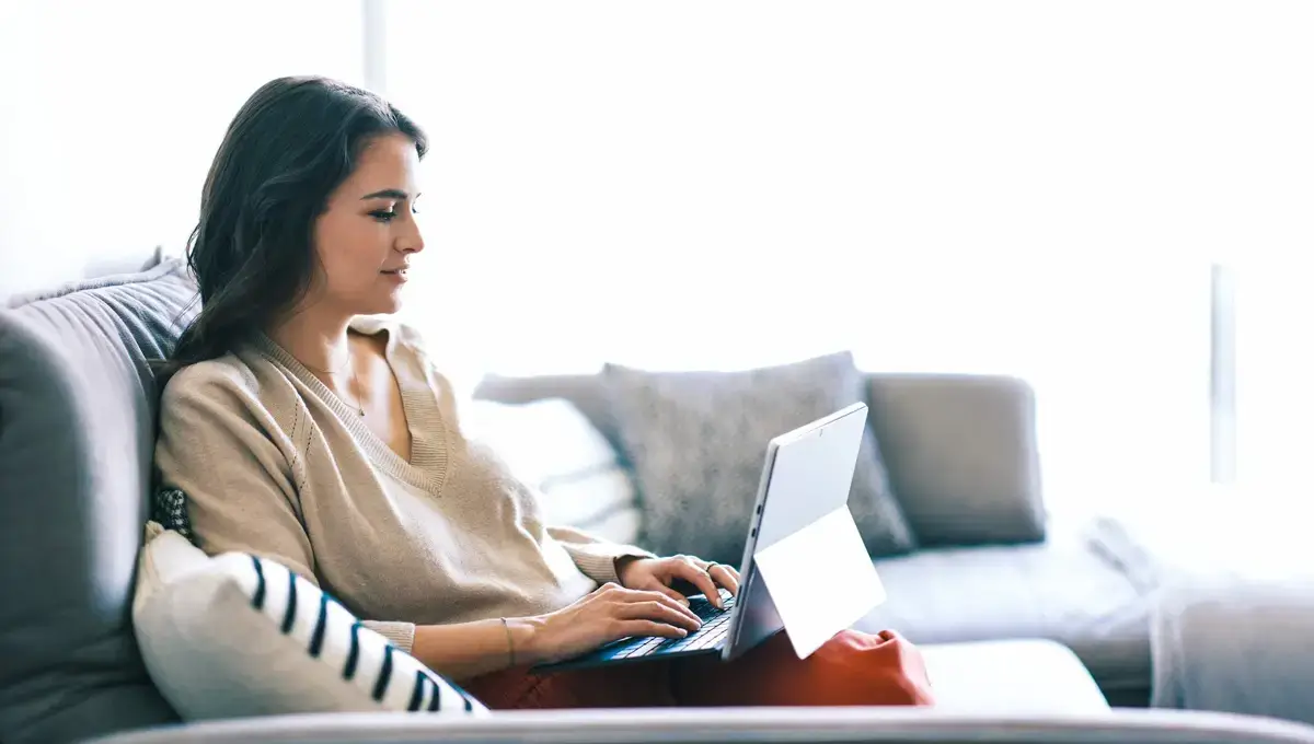 Eine Frau sitzt mit einem Laptop auf einem Sofa