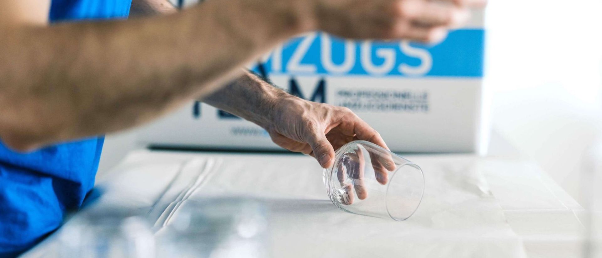 Möbelpacker packt Glas mit Papier ein fpr einen sicheren Transport. DasUmzugsteam