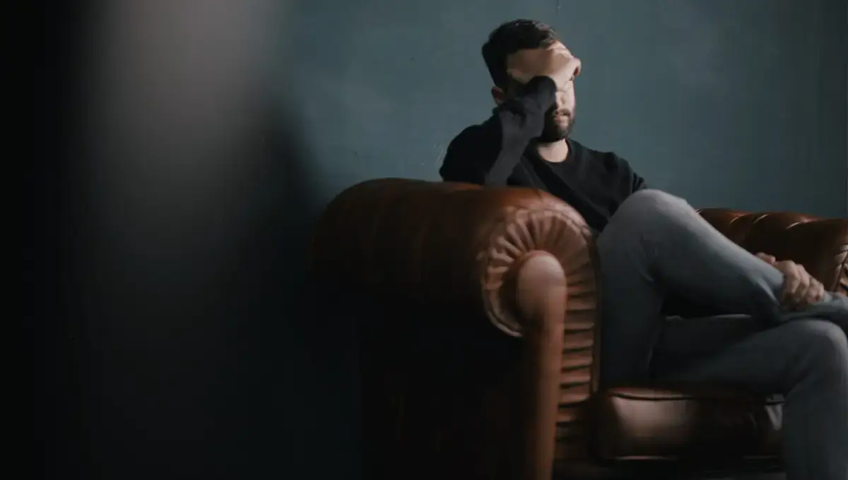 Ein Mann sitzt auf einem Sofa und denkt über die Wohnungsräumung mit DasUmzugsteam- nach, da ein Angehöriger verstorben ist.