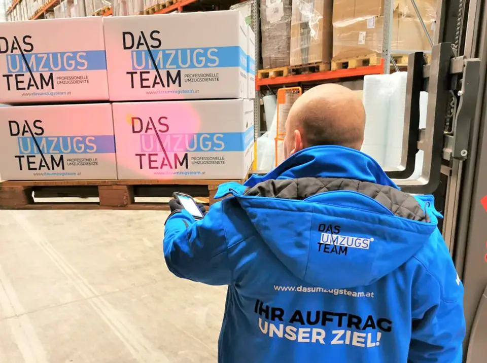 Ein Mann steht vor einem Gabelstapler mit Umzugskartons