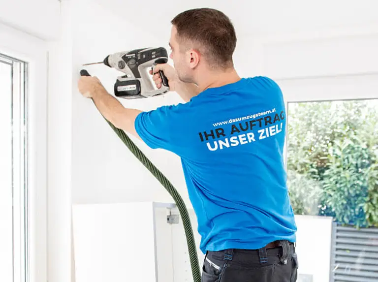 Mitarbeiter von DasUmzugsteam montiert fachgerecht einen Hochschrank an der Wand.