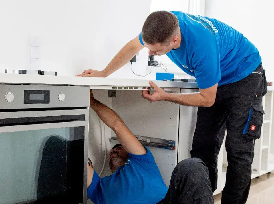 Zwei Männer bei der Küchenmontage. Sie montieren das Induktionsfeld in einer Küche