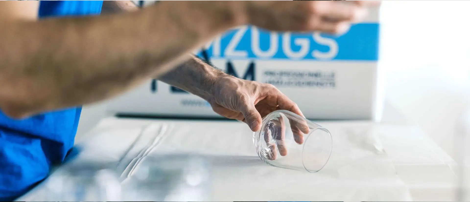 Möbelpacker packt Glas mit Papier ein für einen sicheren Transport. DasUmzugsteam