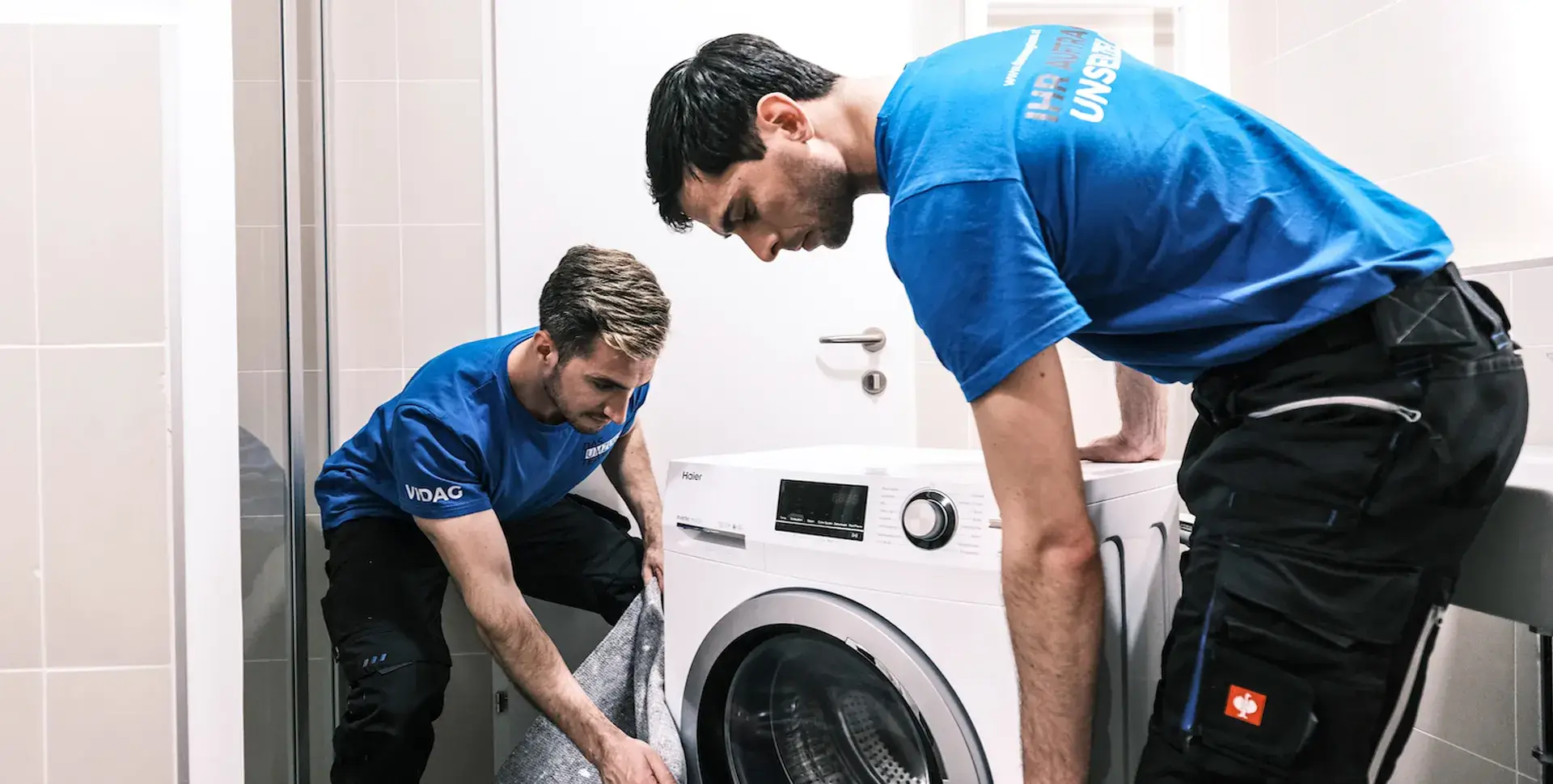 2 Männer von DasUmzugsteam verpacken eine Waschmaschine