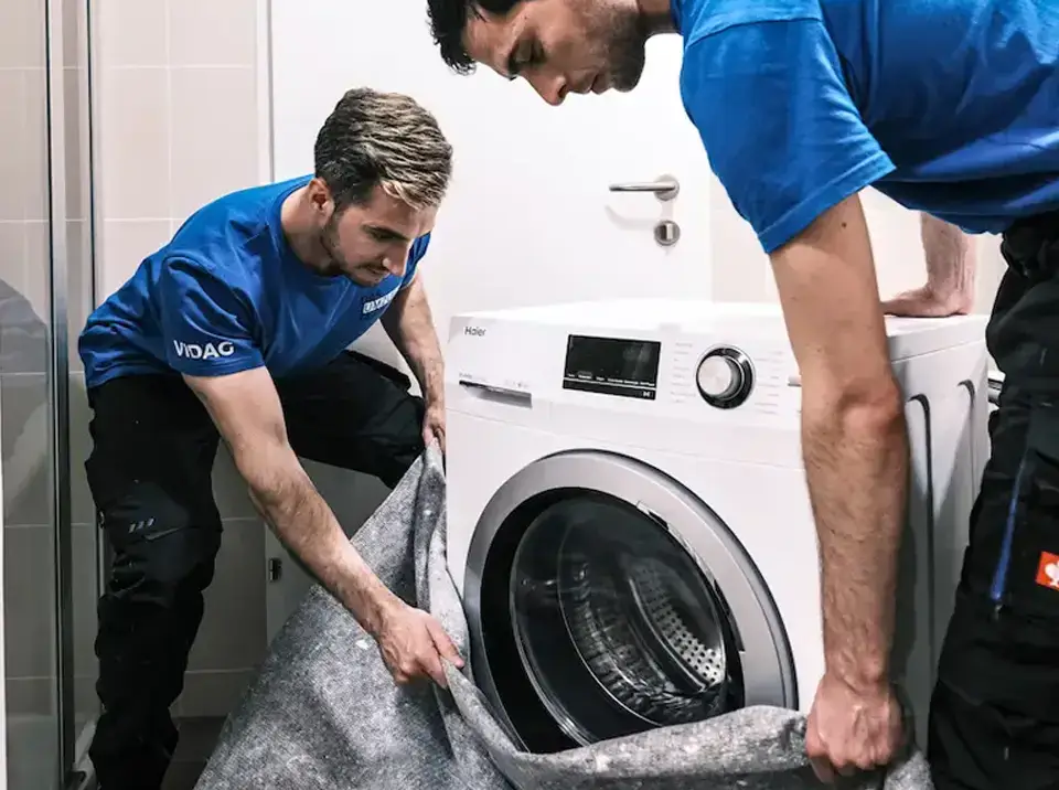 2 Moebelpacker verpacken eine Waschmaschine