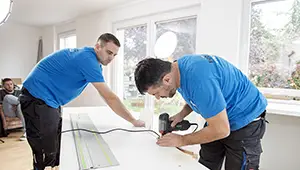 Ikea Küche montieren lassen: 2 Monteure in Arbeitskleidung schneiden die Arbeitsplatte einer Küche zurecht.
