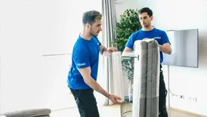 2 Umzugshelfer von DasUmzugsteam verpacken ein Sofa
