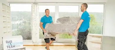 Zwei Umzugshelfer tragen ein Sofa sicher die Treppe hinauf